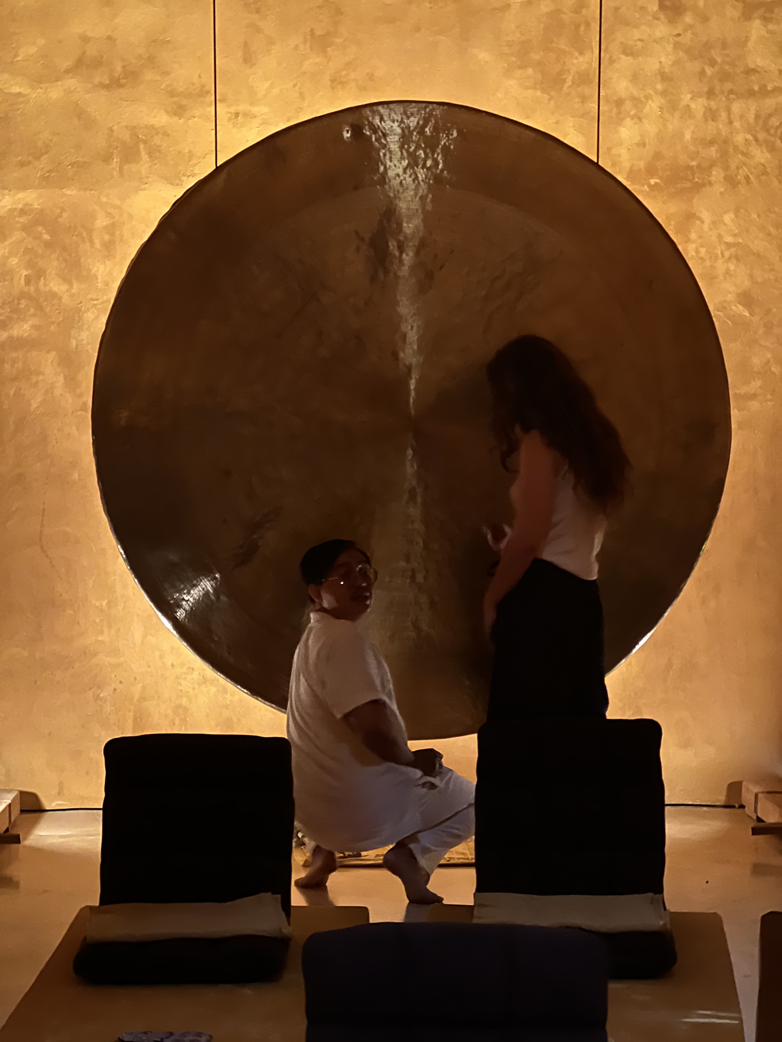 Goni setting up singing bowls and candles in a softly lit room