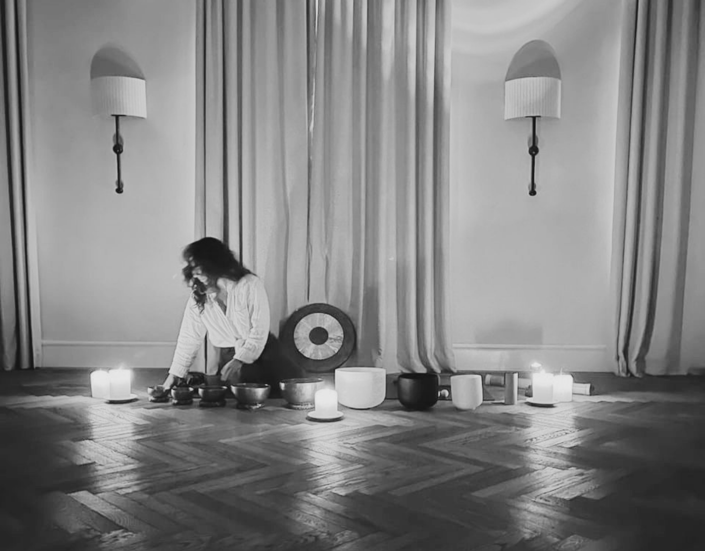Goni setting up singing bowls and candles in a softly lit room