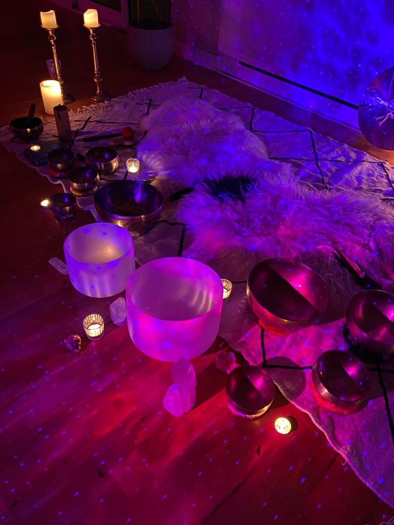 Goni setting up singing bowls and candles in a softly lit room