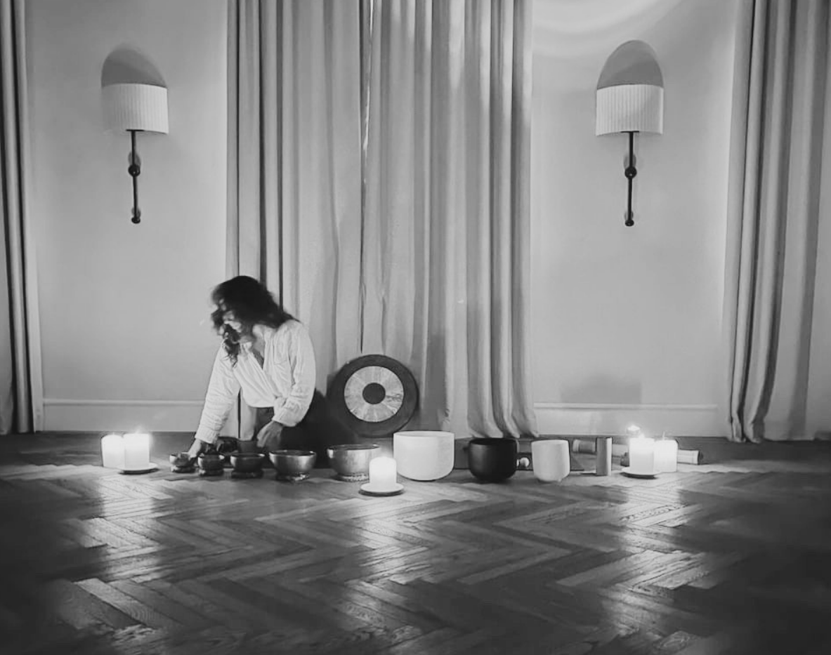 Goni setting up singing bowls and candles in a softly lit room